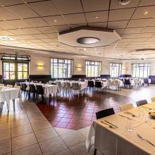 Ingerichte feestzaal met gedekte tafels bij Den Bakker