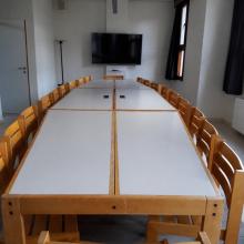 Kleine vergaderzaal met lange tafel en smart-tv