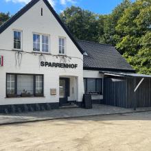 Witte gevel en ingang van Sparrenhof in Oordegem