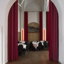 Kloosterkapel met rode gordijnen en gedekte ronde tafels