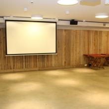 Lege bijeenkomstruimte met projectiescherm en houten wanden