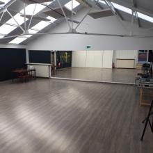 Studio B met houten vloer en spiegels, kleine reflectie en fotoposters digitaal verwijderd