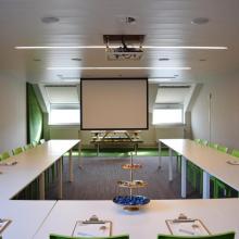 Vergaderopstelling met groene stoelen en projectiescherm