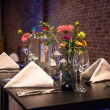 Bloemendecoratie en glazen op een feesttafel bij Hof van Boeres