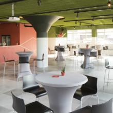 Lichte zaal met groene plafondaccenten en hoge ronde tafels
