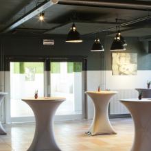 Industriële zaal met hoge tafels en zichtbare plafondstructuur