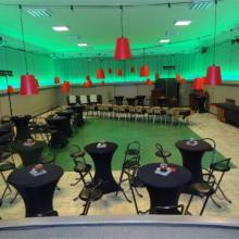 Grote zaal met podium, hoge tafels en sfeerverlichting