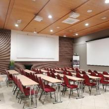 Opleidingszaal met rode stoelen en projectieschermen
